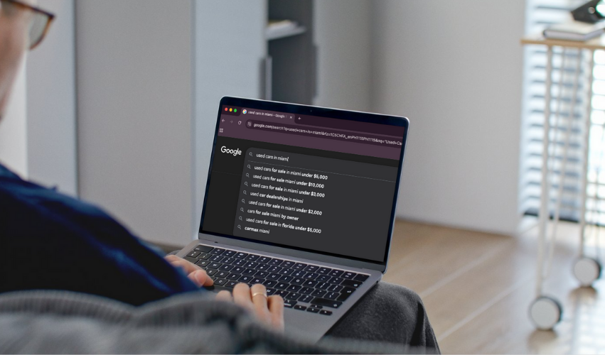 Person browsing used car searches on laptop for nearby dealerships