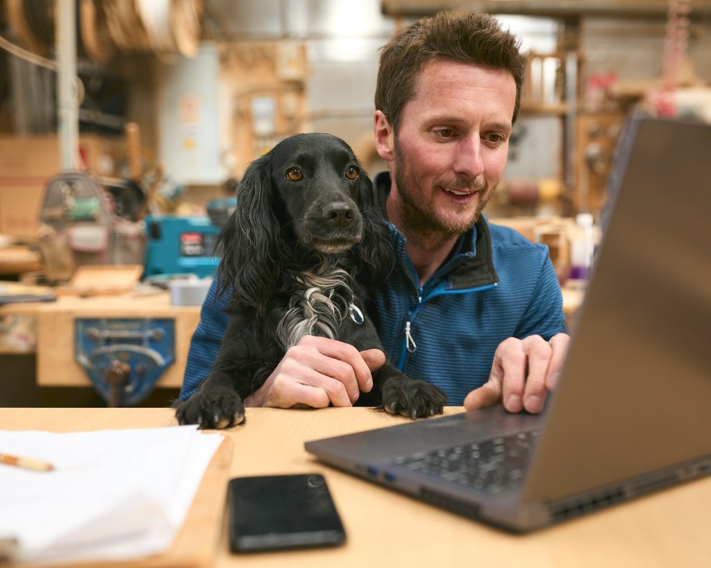 Man with black dog researching pet brand SEO strategies online