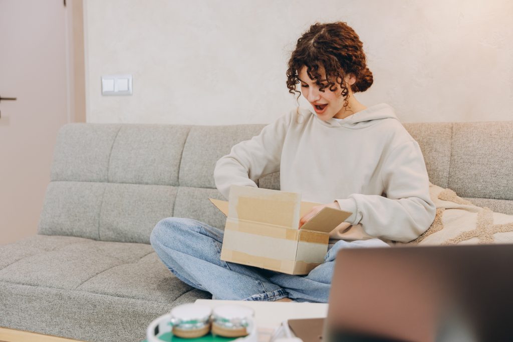 Happy woman opening a CPG subscription box at home